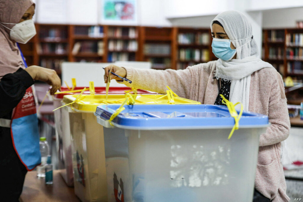 A mask-clad voter casts her ballot while voting in an election for the Tripoli Municipal Council, in Libya's capital on February 6, 2021. (Photo by Mahmud TURKIA / AFP)